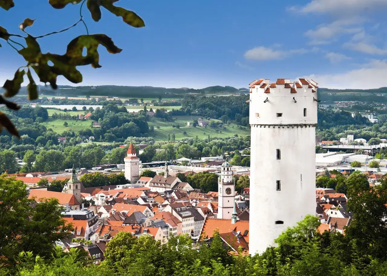 Der wei&szlig;e Mehlsack Ravensburg ragt &uuml;ber die D&auml;cher der Stadt. Im Hintergrund gr&uuml;ne H&uuml;gel und blauer Himmel.