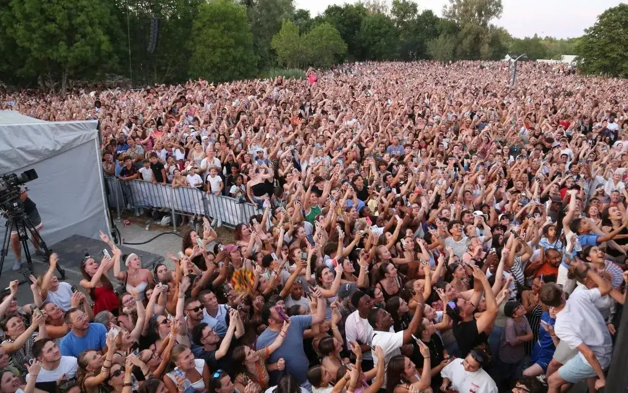 Foule immense en délire devant un disc jockey célèbre, tous les bras levés et smartphones en l'air pour immortaliser l'instant.