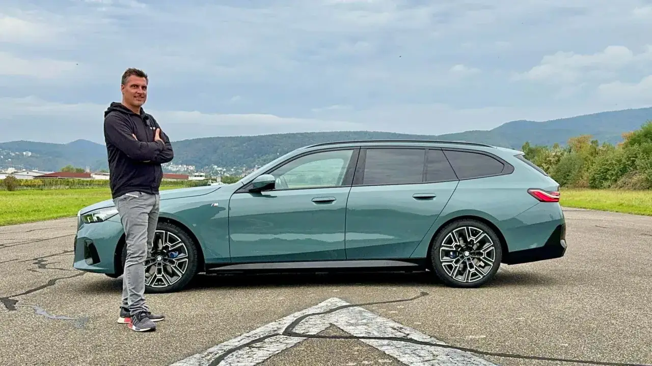 Mann steht neben einem grünen BMW 540d Kombi. Der BMW 540d testet seine Leistung auf einer Teststrecke.
