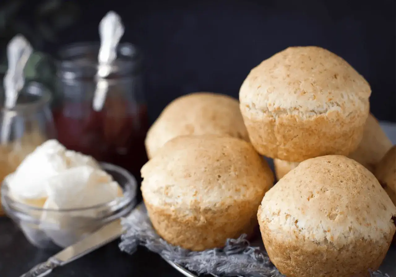 Glutenfria scones fiberhusk, fluffiga och gyllene, serveras med sylt och grädde. Perfekt för fikat!