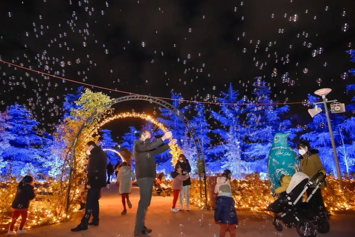 Gente disfrutando de burbujas mágicas en el parque de Navidad de Torrejón, rodeados de luces azules y doradas.