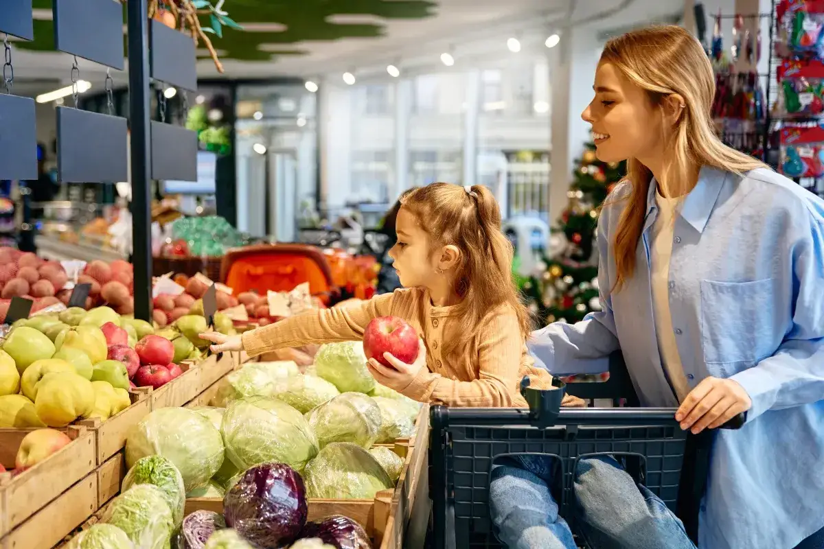 Mama z córką wybierają jabłka w sklepie. Czy w Wielką Sobotę się pracuje? Czasem trzeba zrobić zakupy.