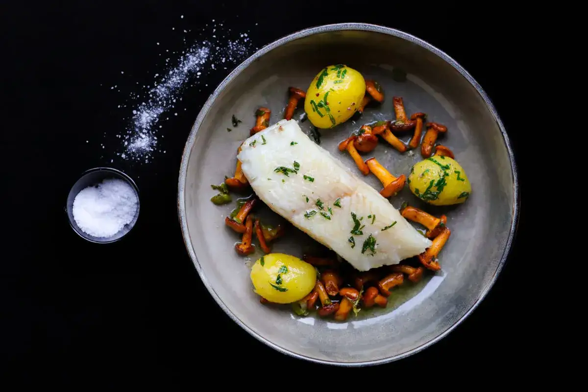 Ein köstliches Heilbutt-Rezept: Gebratener Heilbutt mit kleinen Kartoffeln und Pfifferlingen, garniert mit frischen Kräutern.