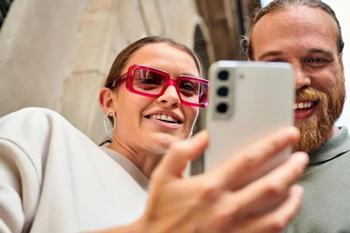 Uśmiechnięta para robi selfie telefonem. Ona ma różowe okulary, on rudą brodę. Idealny duet z **multisim t mobile**.