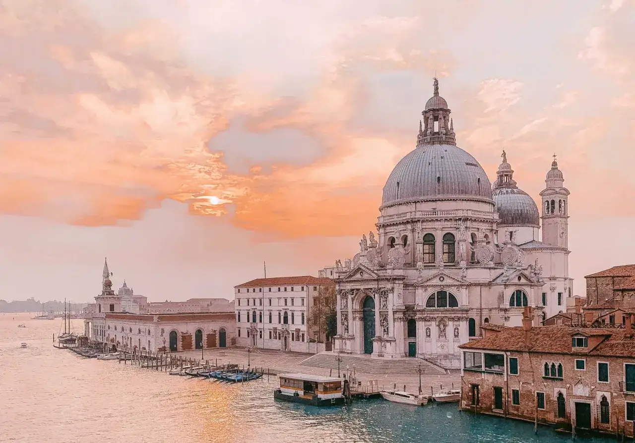 Zachód słońca nad Bazyliką Santa Maria della Salute. To jedno z miejsc, które koniecznie trzeba zobaczyć w Wenecji, by poczuć jej magię.