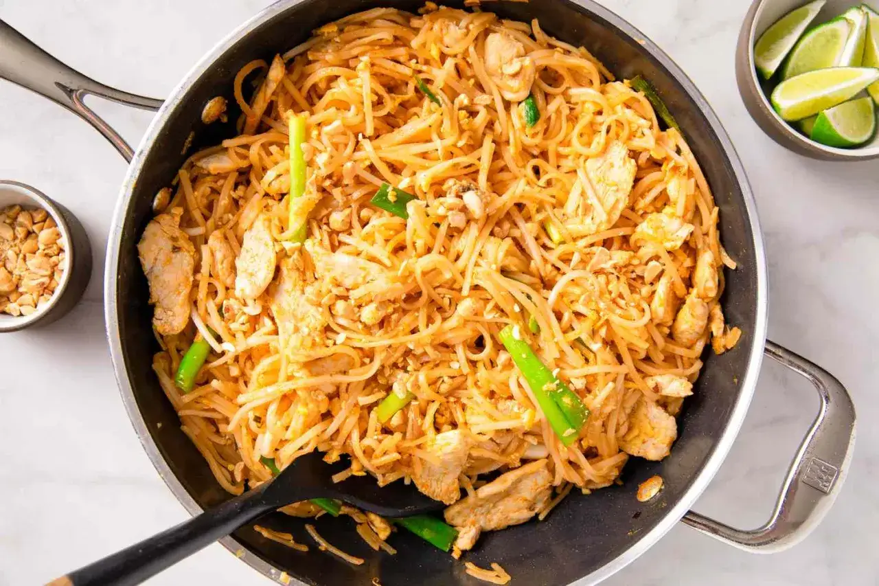 En stor panna med kyckling-pad thai, redo att serveras. Ett enkelt pad thai recept som passar alla.