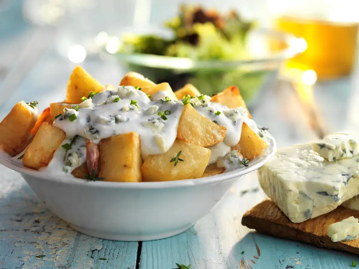 Patatas fritas crujientes ba&ntilde;adas en una cremosa salsa de queso azul, un delicioso plato de patatas roquefort.