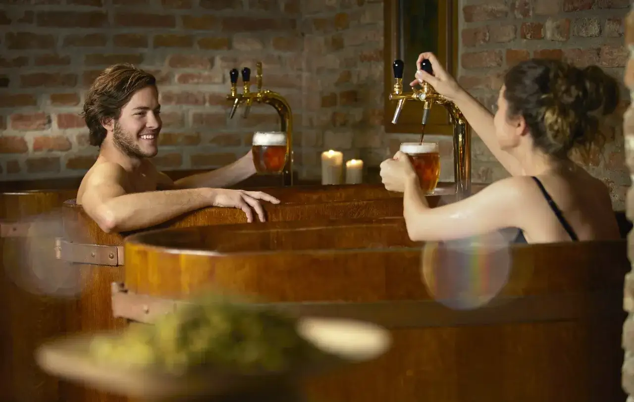 Ein Paar genießt ein Bierbad im Chodovar Hotel. Sie zapfen sich frisches Bier direkt in ihre Holzbottiche.