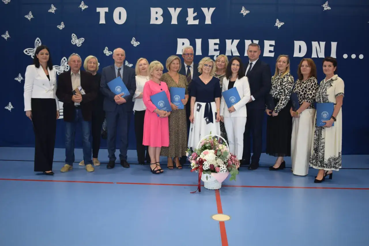 Uroczyste zakończenie roku szkolnego. Grupa osób odbiera dyplomy i gratulacje.
