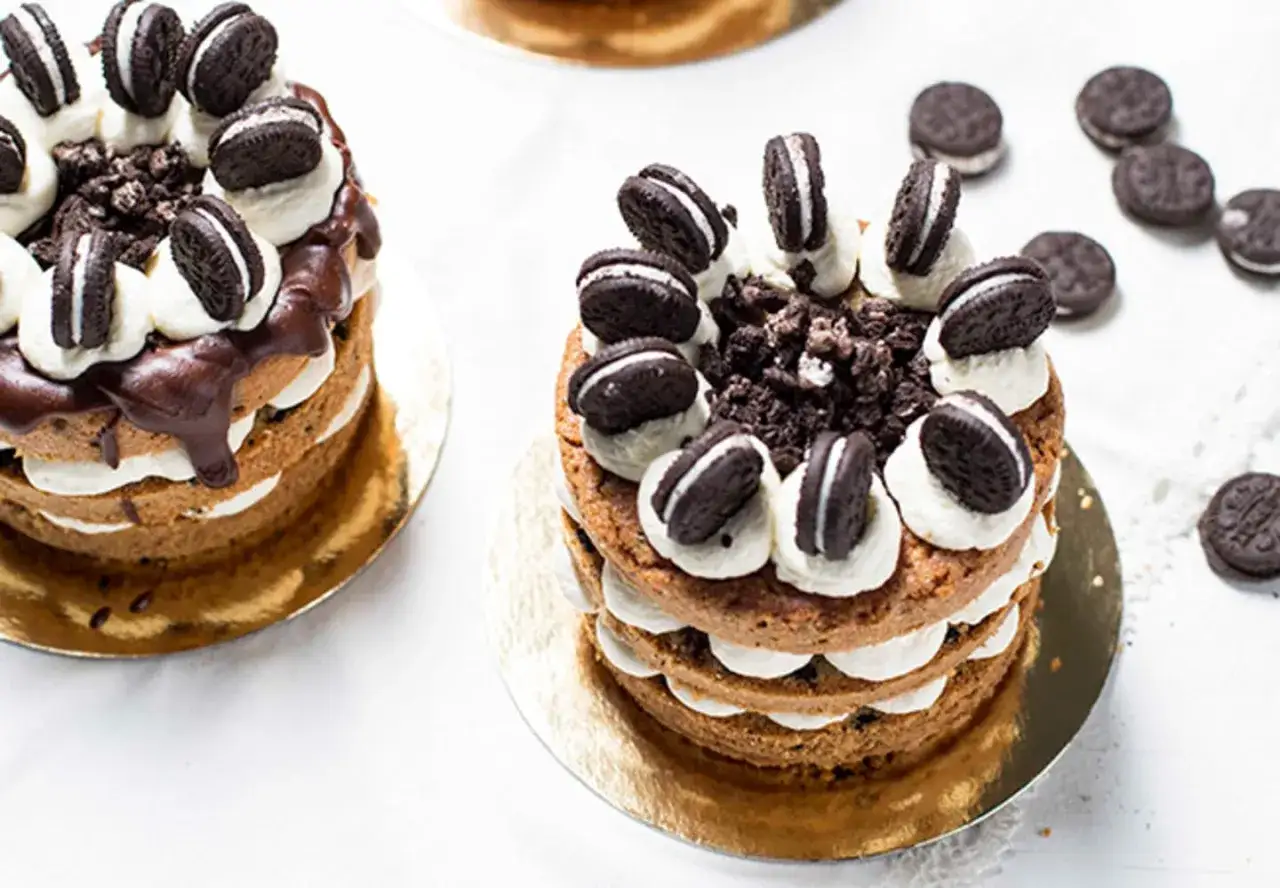 Två läckra oreo tårtor med chokladmousse och grädde, dekorerade med hela och krossade oreokakor.