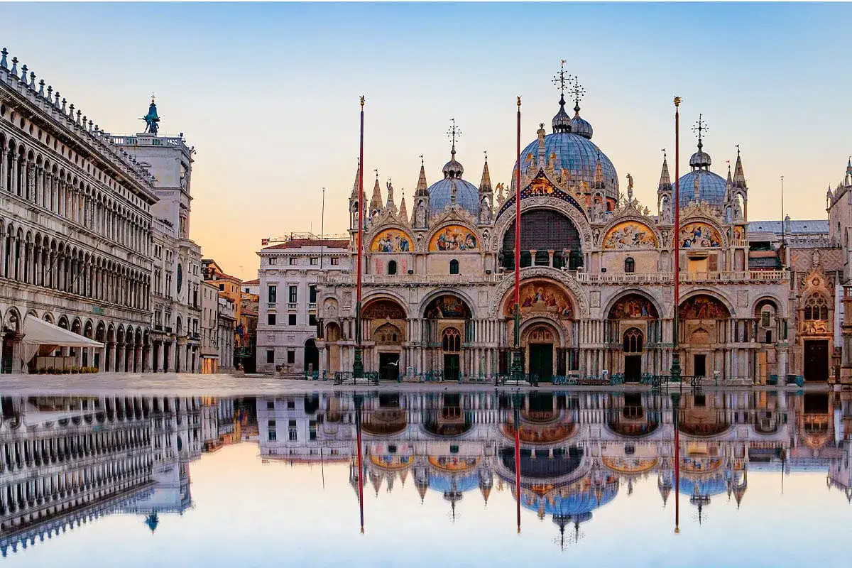 Wenecka Piazza San Marco z odbiciem w wodzie. Bazylika św. Marka w blasku zachodzącego słońca.