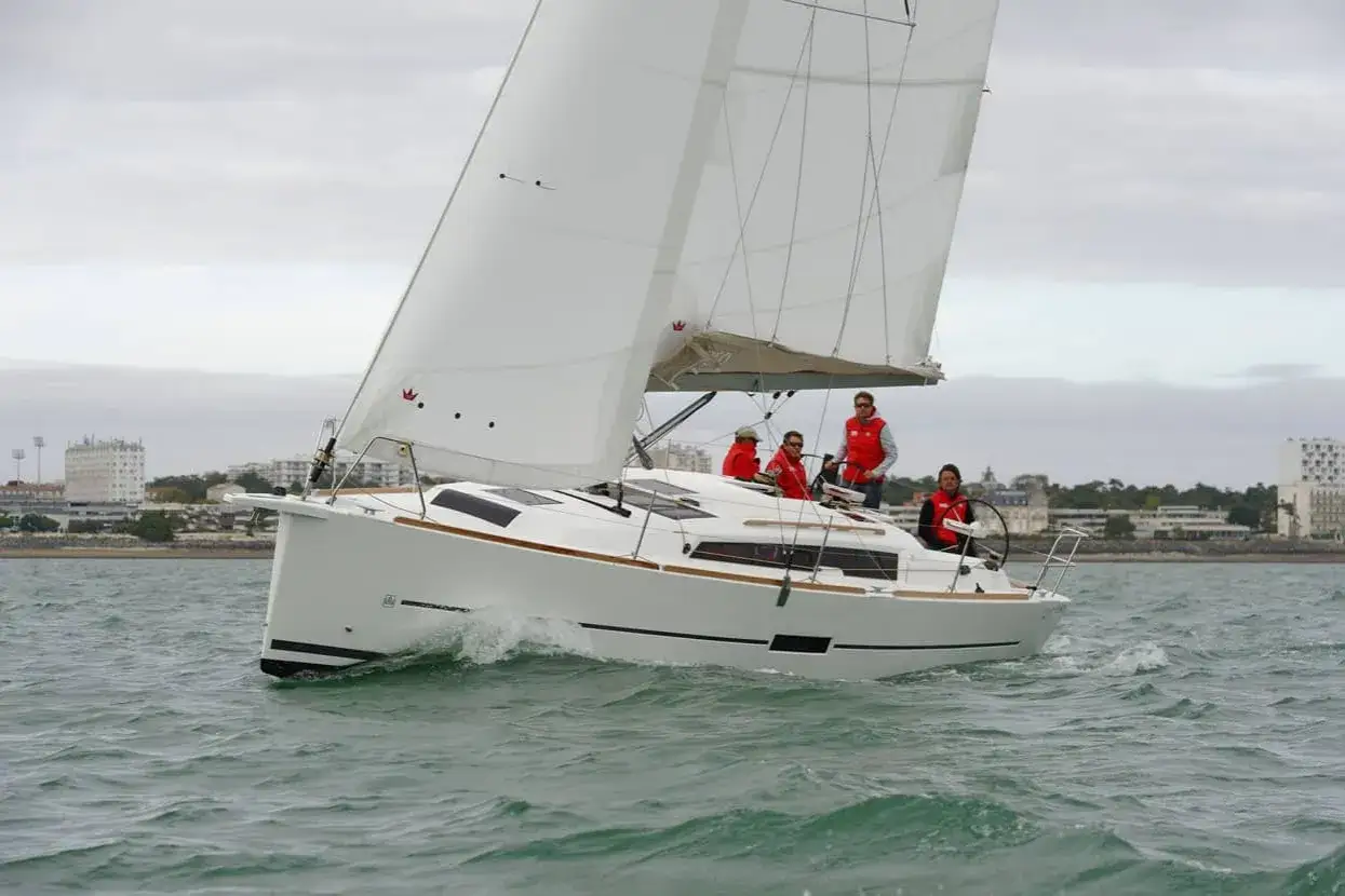 Voile blanche gonflée sur un Dufour 360, équipage en gilets rouges. La fiche technique de ce voilier est impressionnante.