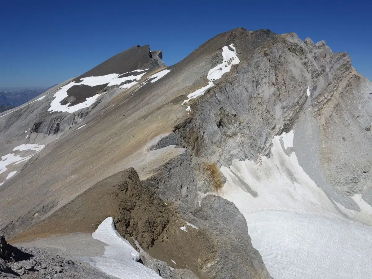 Vue spectaculaire d'une cr&ecirc;te rocheuse et enneig&eacute;e lors d'une barrhorn randonn&eacute;e sous un ciel bleu intense.