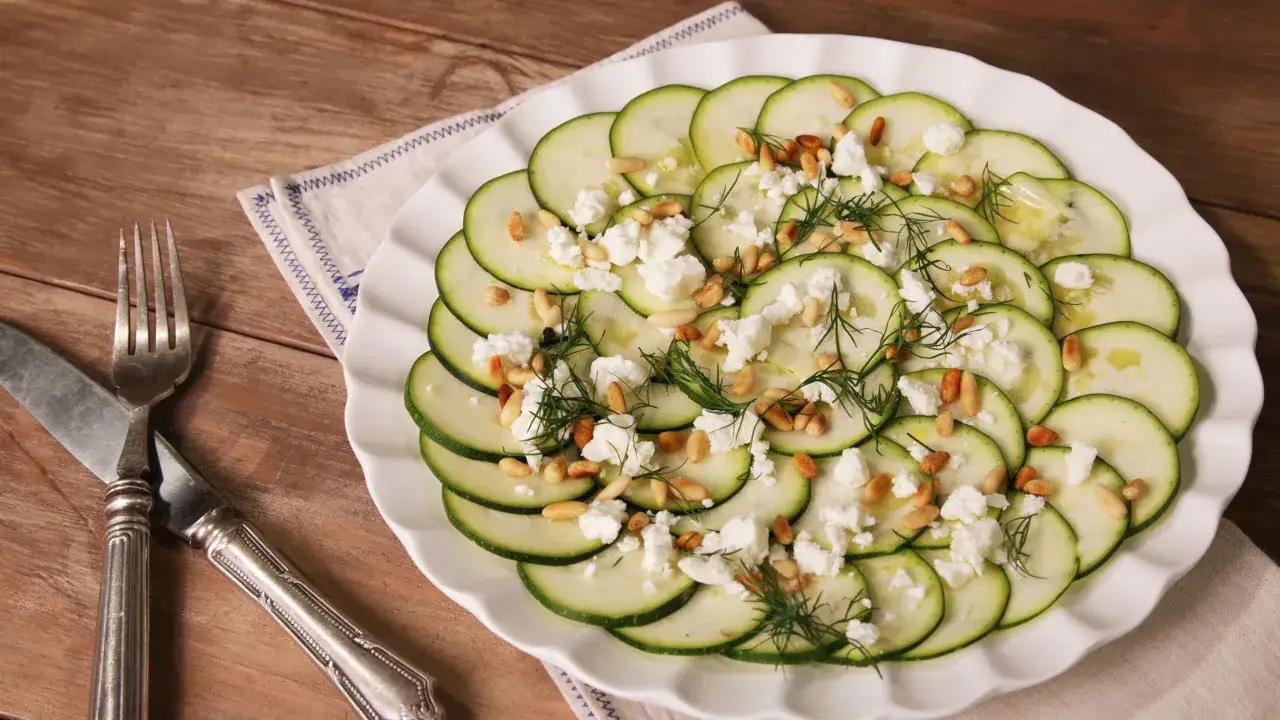 Delicioso carpaccio de calabacín con queso feta desmenuzado, piñones tostados y eneldo fresco, regado con aceite de oliva.