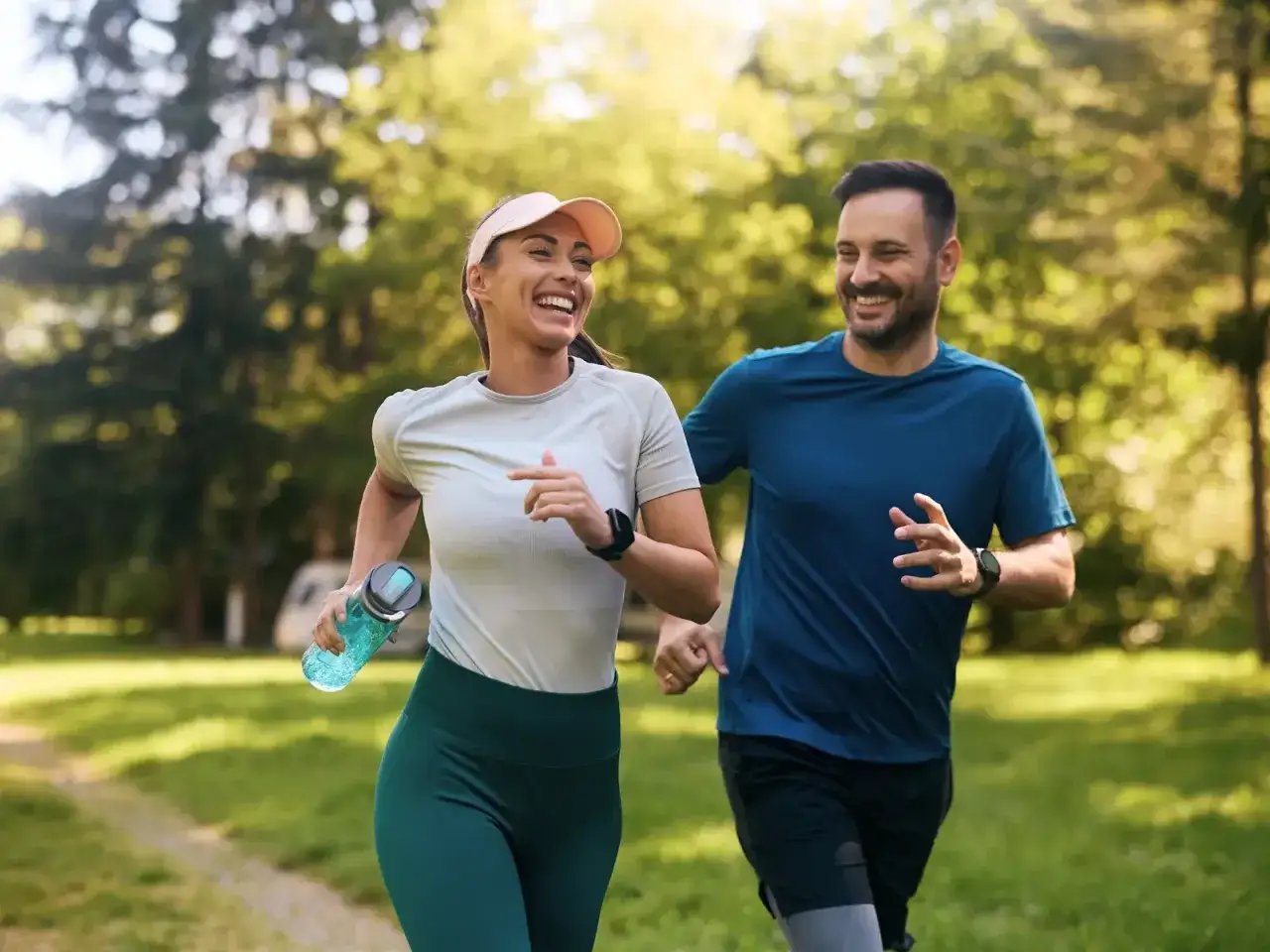 Coppia sorridente che corre nel parco, godendosi i benefici della corsa per la salute e il benessere.