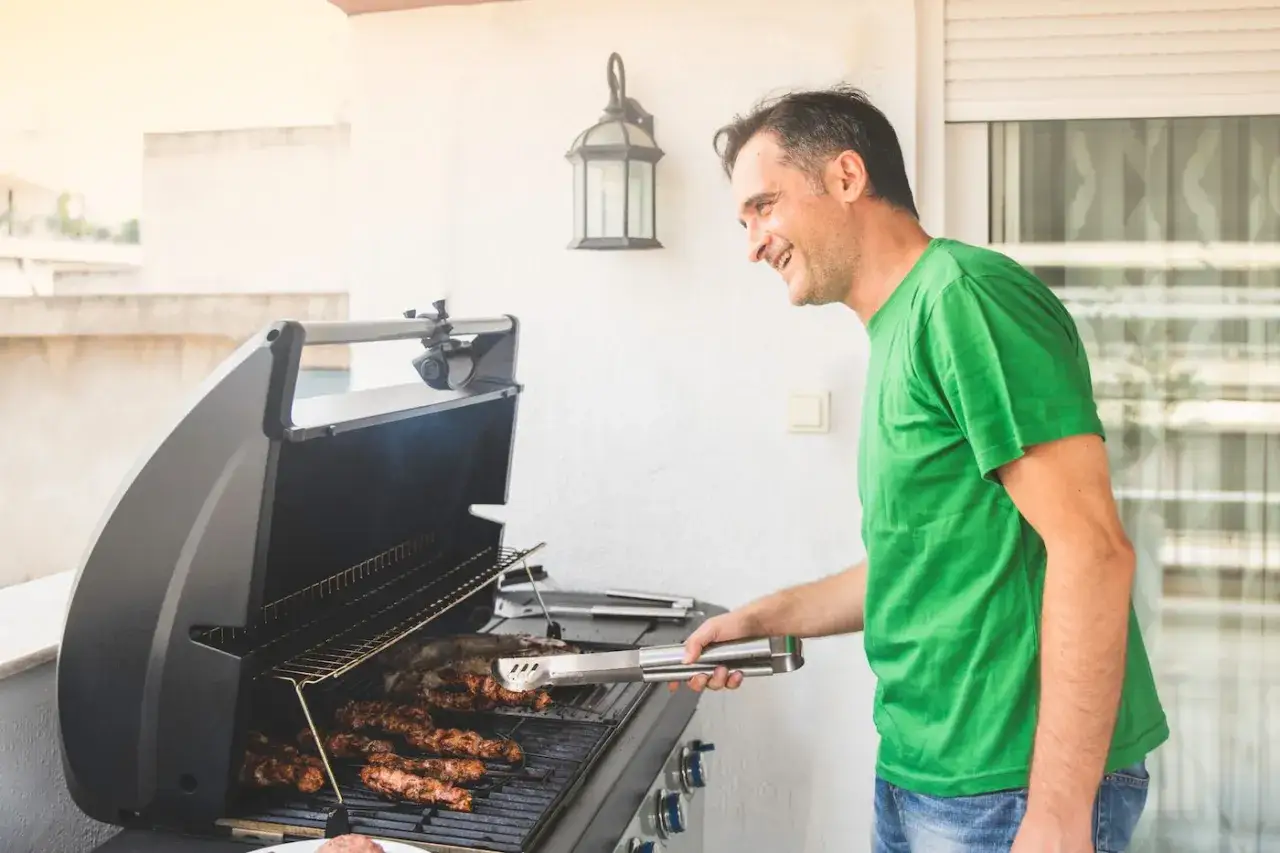 Man grillar korv p&aring; en balkong.