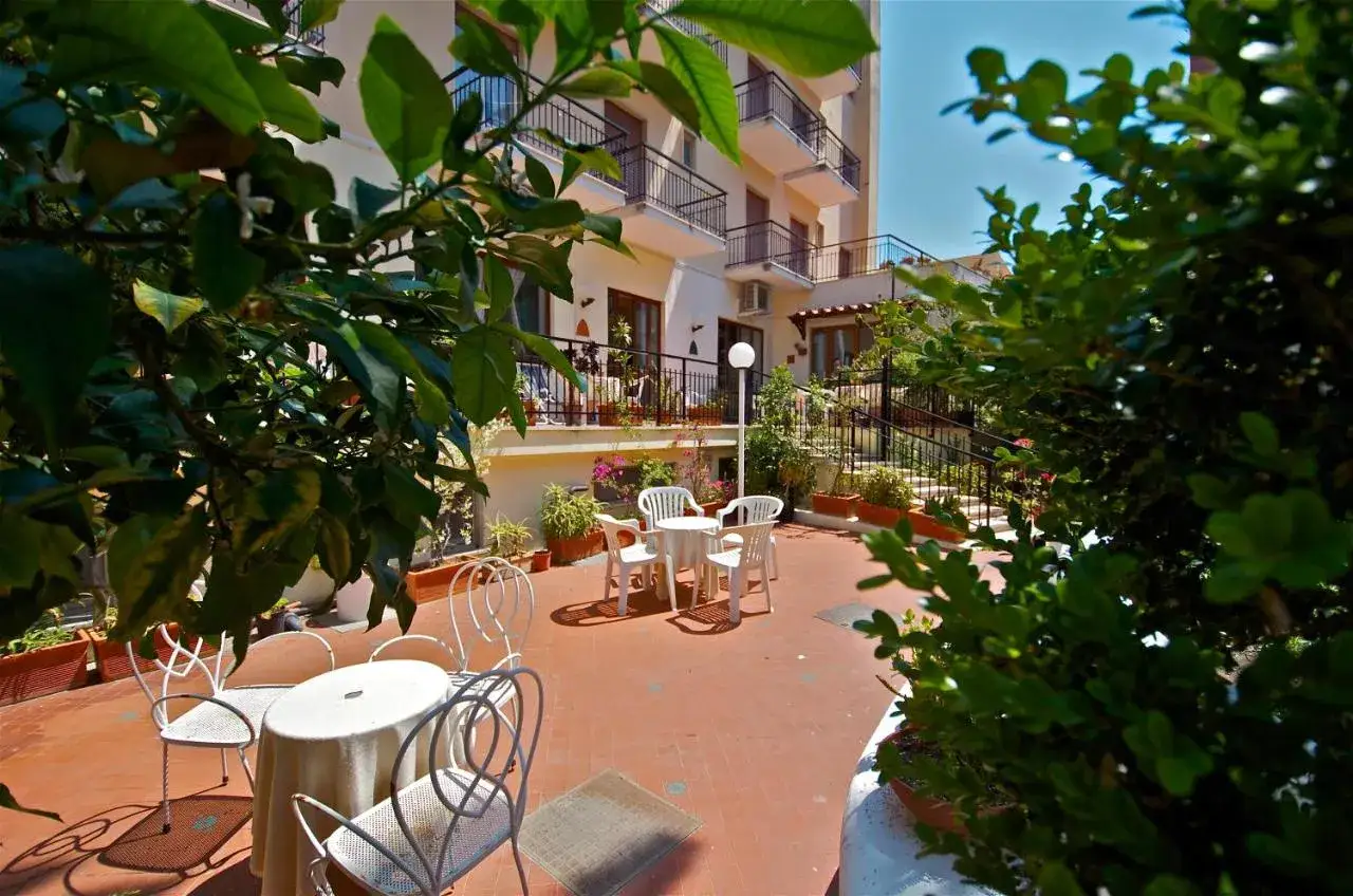 Terrazza fiorita con tavoli e sedie, ideale per un caffè mattutino al **hotel Conte Ischia**.