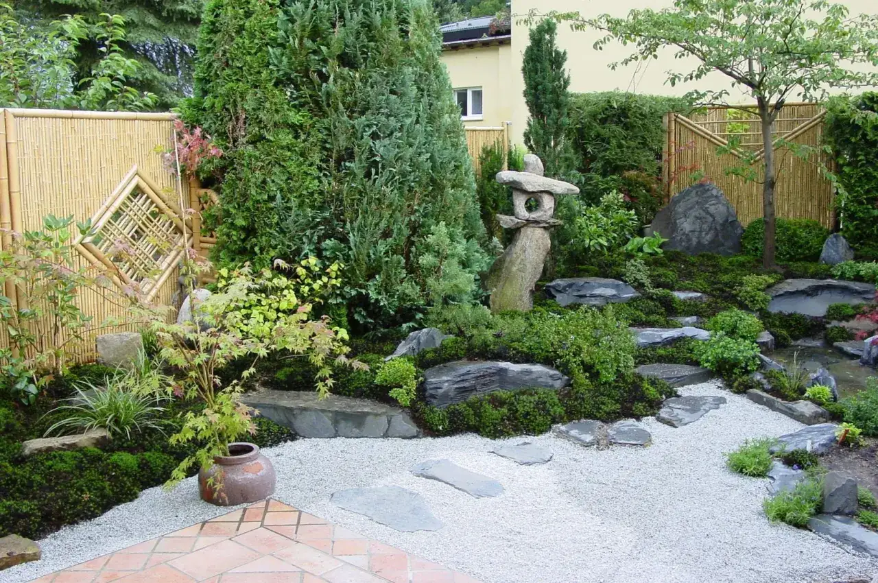 Ein friedlicher japanischer Garten mit Bambuszaun, Steinlaterne, Moos und Kieswegen.