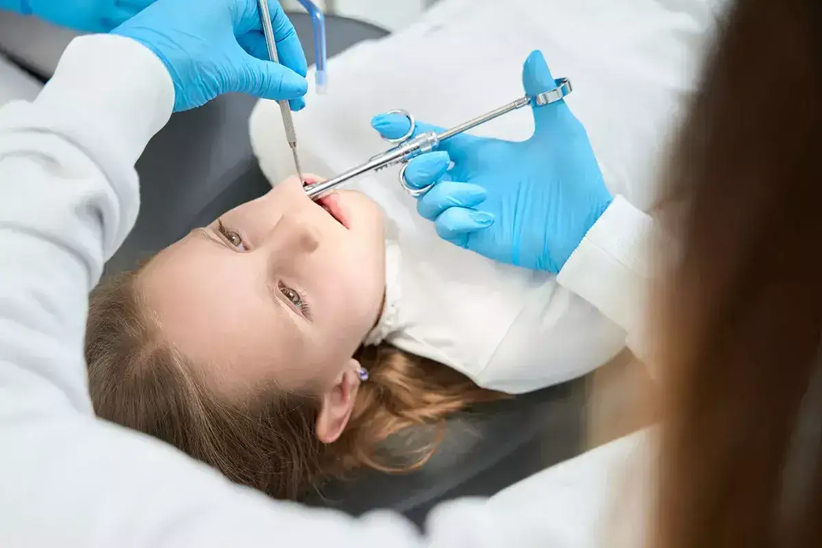 Ni&ntilde;a recibe anestesia dental. El dentista administra la inyecci&oacute;n, minimizando los efectos secundarios de la anestesia dental.