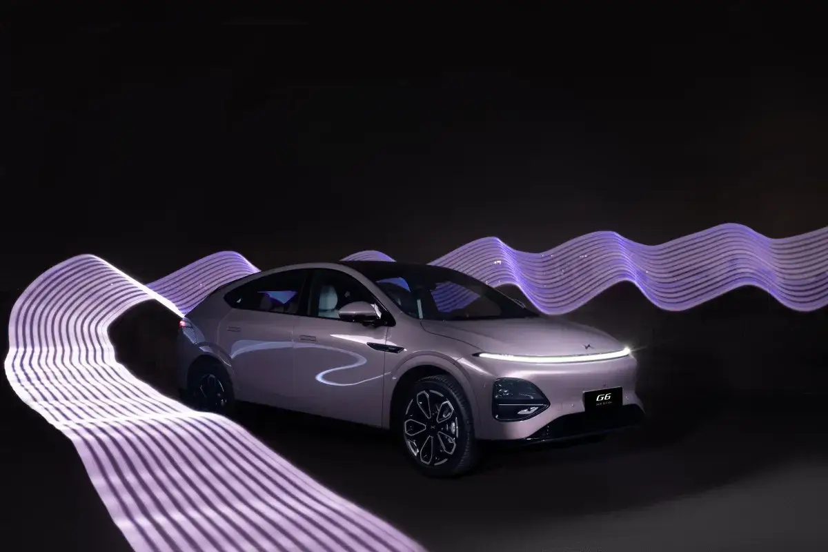 Le Xpeng G6, un SUV électrique, est mis en valeur par des traînées de lumière violettes ondulantes sur fond noir, créant une scène futuriste.