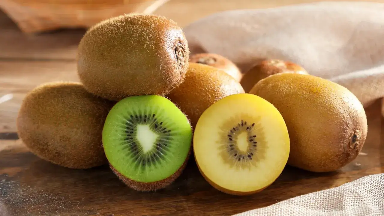 Kiwi verde y dorado, uno cortado, mostrando su interior vibrante. El kiwi es cítrico, una explosión de sabor tropical.