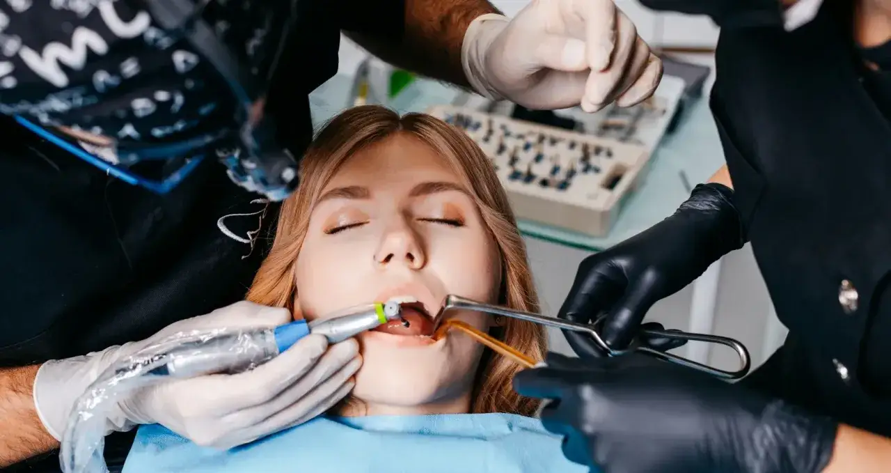Zabieg stomatologiczny z zastosowaniem znieczulenia nasiękowego. Pacjentka z zamkniętymi oczami, dentysta wykonuje zabieg.