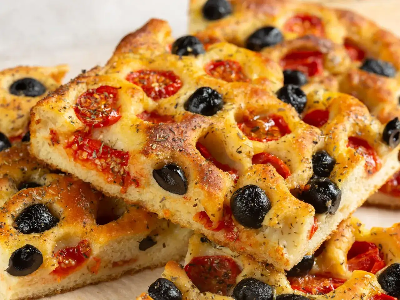 Focaccia rossa con pomodorini e olive nere, fragrante e profumata, pronta per essere gustata.