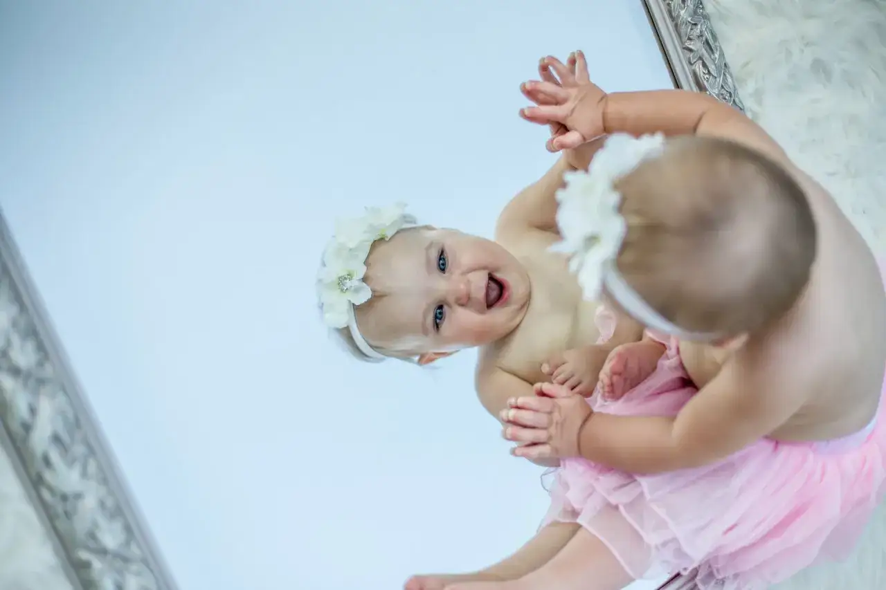 Bambina con coroncina di fiori e tutù rosa, riflessa in uno specchio. Un'immagine che cattura la gioia e la crescita dei bambini.