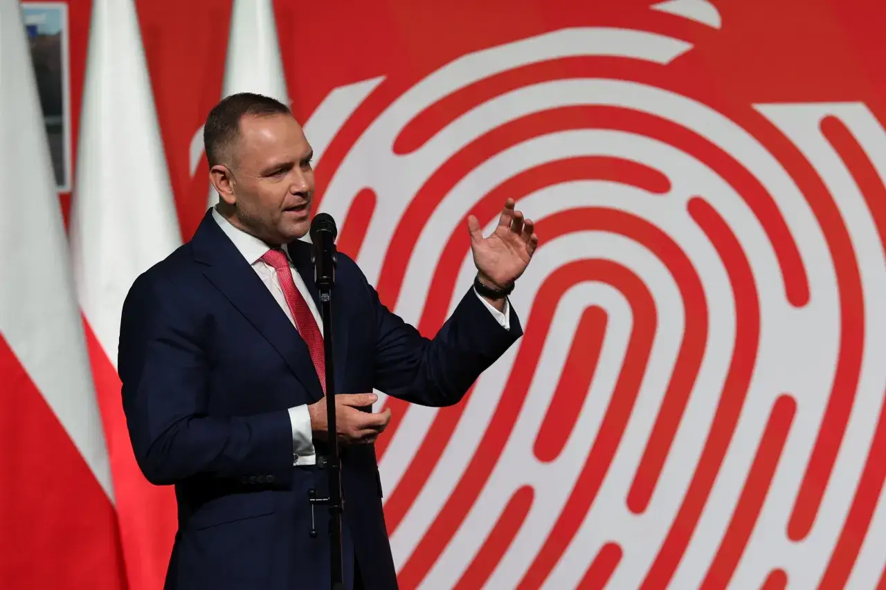 Mężczyzna w garniturze przemawia przy mikrofonie na tle biało-czerwonych flag i wzoru odcisku palca. Czy prezydent planuje powołanie nowej rady konsultacyjnej z udziałem młodych liderów?