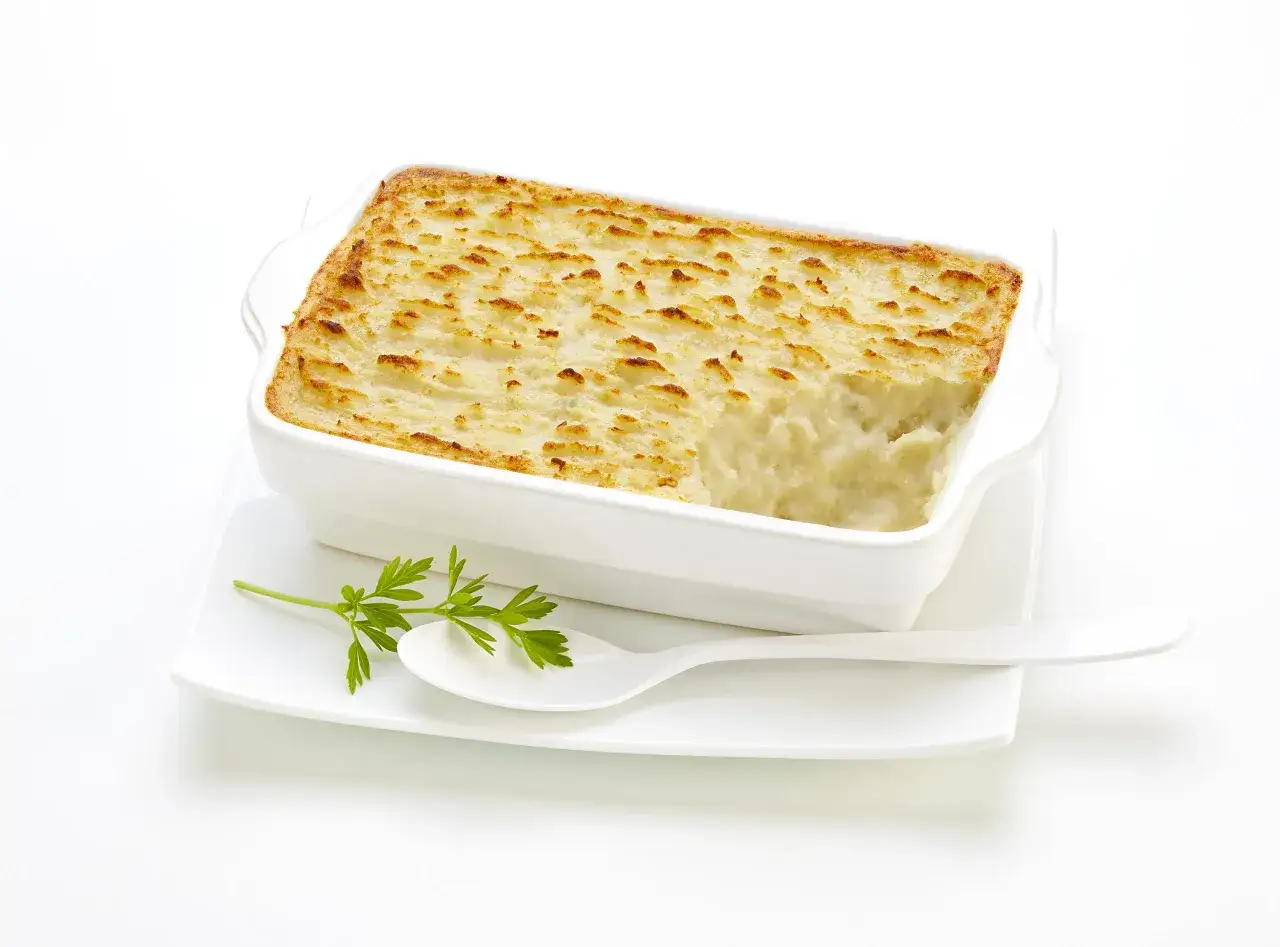 Un plat blanc rectangulaire contient une brandade de morue gratin&eacute;e. Une cuill&egrave;re blanche et une branche de persil reposent sur une assiette.