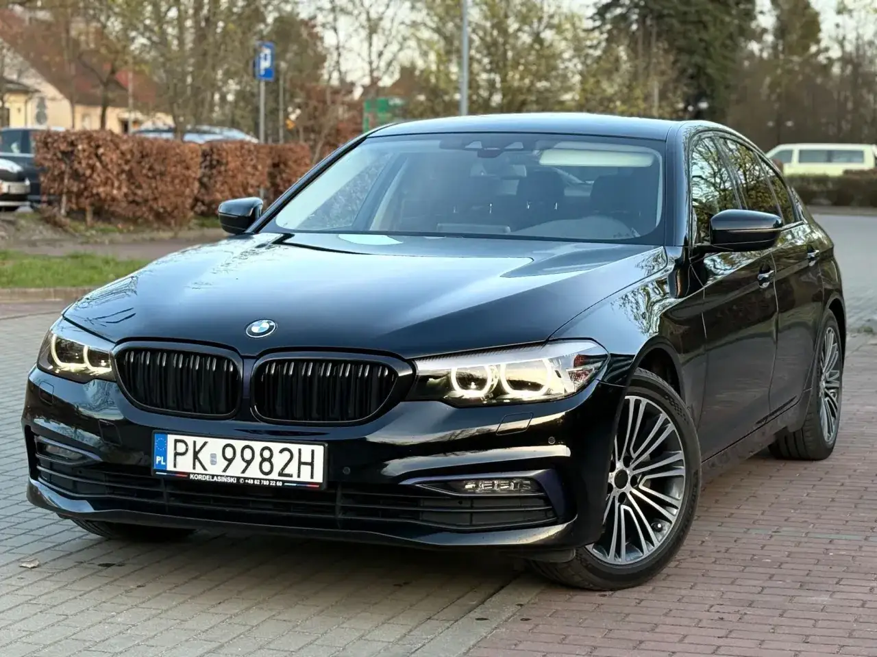 Czarny BMW M5 G30 z polskimi tablicami rejestracyjnymi PK 9982H zaparkowany na bruku.