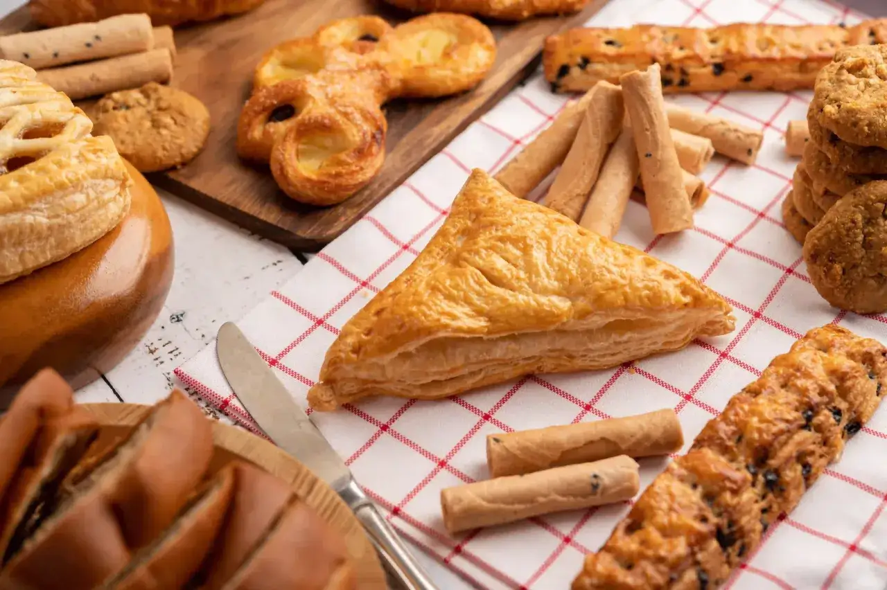 Un assortiment de viennoiseries dor&eacute;es, dont un triangle de p&acirc;te feuillet&eacute;e croustillante, des biscuits et des rouleaux sabl&eacute;s.