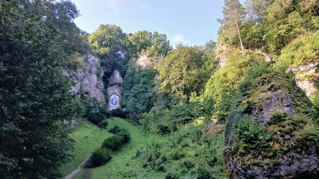 Malownicza Dolina Mnikowska z kapliczką Matki Boskiej ukrytą w skale. Zielone zbocza i skalne ściany tworzą niezwykły krajobraz.