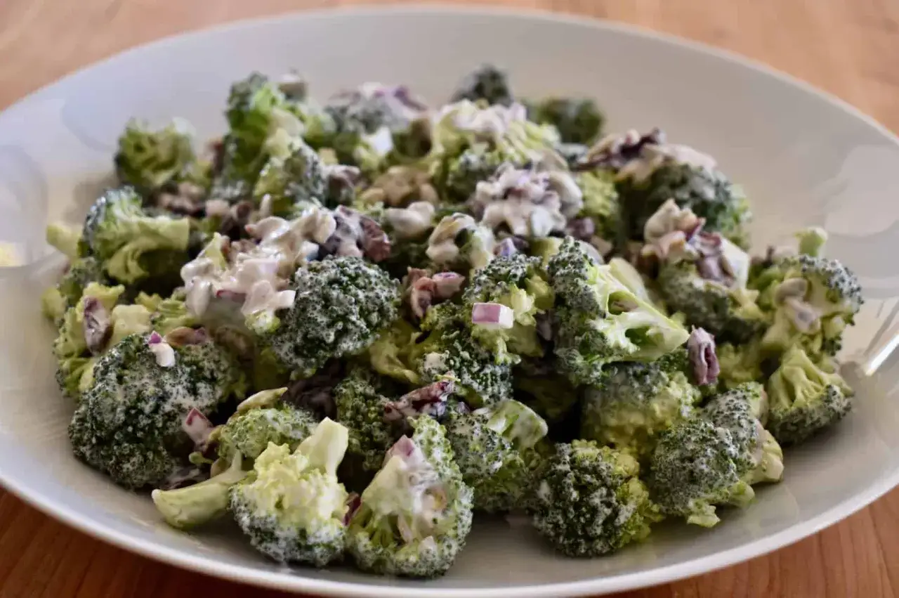 Frischer Brokkolisalat mit cremiger Soße und roten Zwiebeln. Perfekt, um Brokkoli roh zu essen und Vitamine zu tanken.