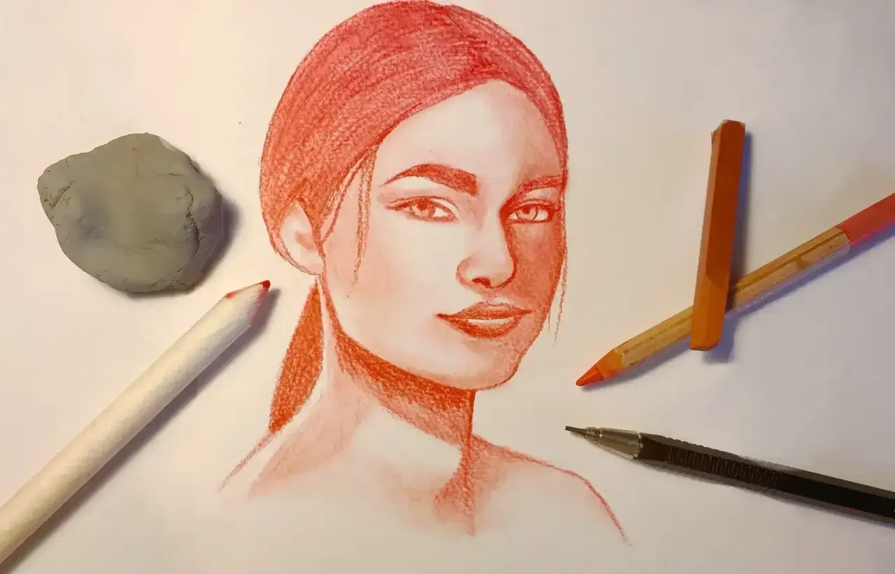 Un portrait expressif r&eacute;alis&eacute; au dessin sanguine, entour&eacute; de ses outils : gomme, crayons et porte-mine.