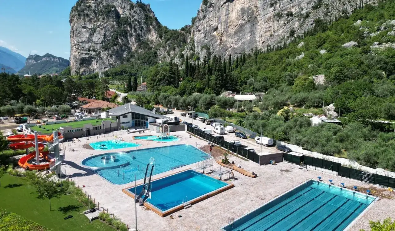 Basen z atrakcjami i zjeżdżalniami, otoczony zielenią i górami. Idealne miejsce na rodzinny camping Arco.