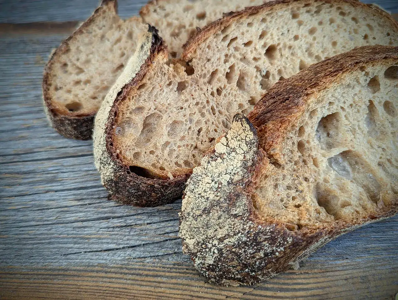 Schnittfl&auml;chen von rustikalem Ruchbrot mit knuspriger Kruste auf Holz. Ein tolles Ruchbrot Rezept!
