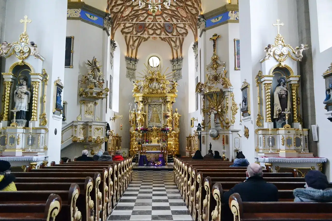 Wnętrze kościoła z ołtarzem głównym i bocznymi kaplicami. W centralnym punkcie znajduje się obraz Matki Boskiej Kodeńskiej.