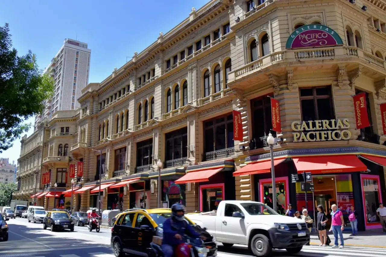 Ulica w Buenos Aires z Galerią Pacifico. Ruch uliczny, taksówki i motocykliści. Ceny w Argentynie mogą być różne, ale zakupy tutaj to przeżycie.