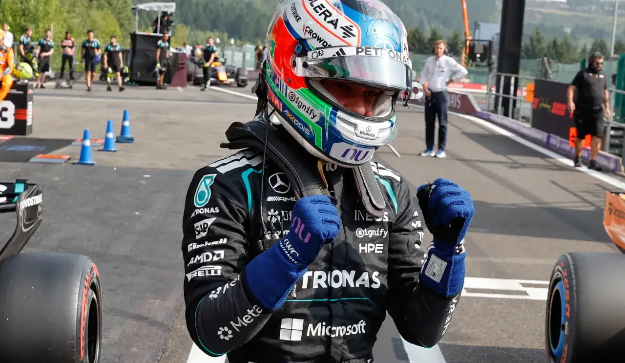 Piloto de F&oacute;rmula 1 con casco y guantes azules, listo para la clasificaci&oacute;n hoy.
