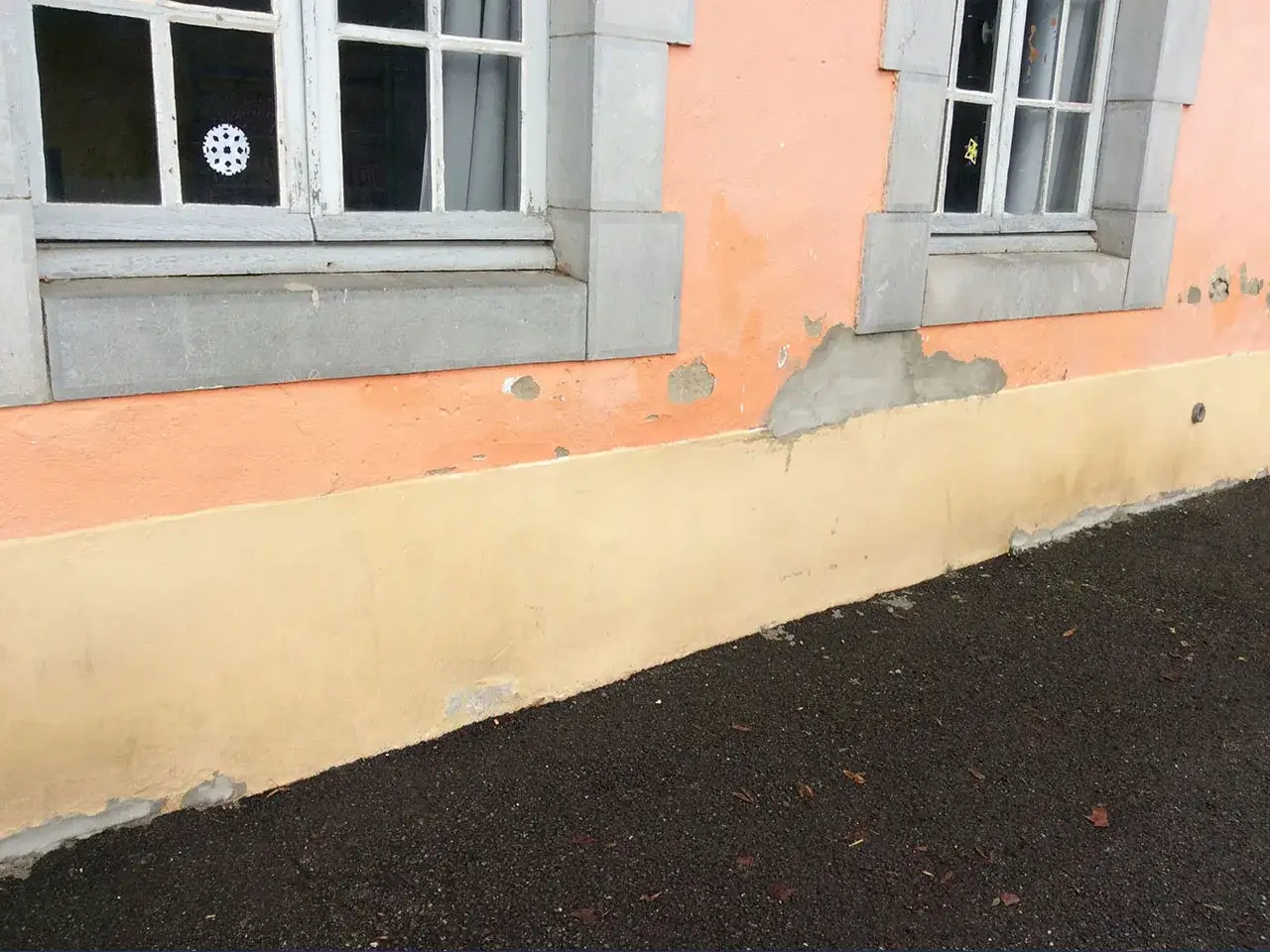 D&eacute;t&eacute;rioration du cr&eacute;pi due &agrave; la remont&eacute;e capillaire du sol. Le bas du mur est d&eacute;color&eacute; et &eacute;caill&eacute;, pr&egrave;s du sol sombre.