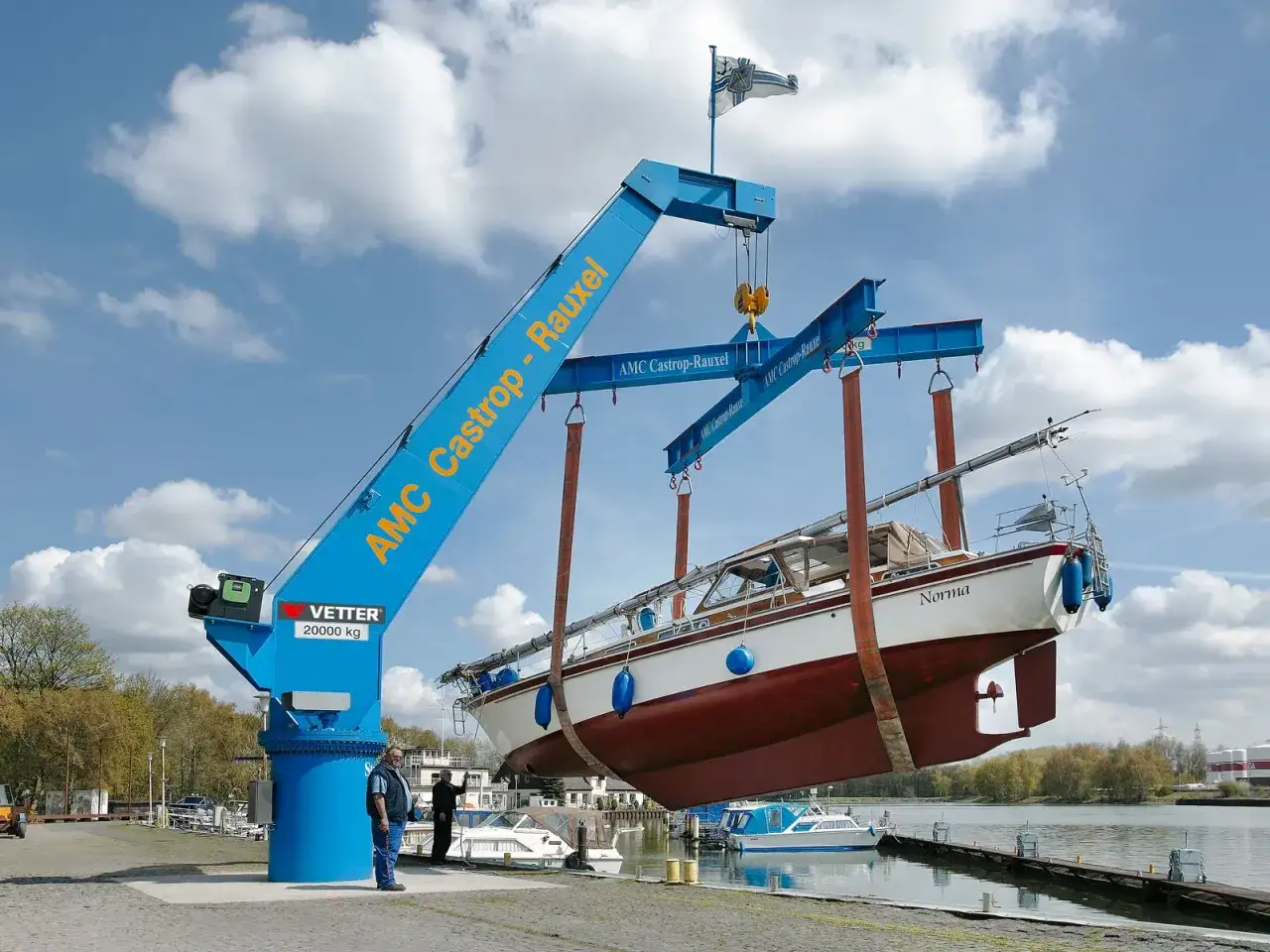 Ein großer blauer Boot kran hebt ein Segelboot namens