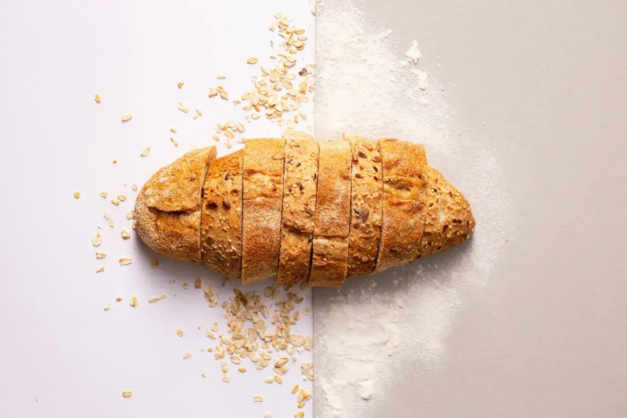 Pain de seigle tranché, parsemé de flocons d'avoine et de farine. Un délice sans gluten pour les gourmands.