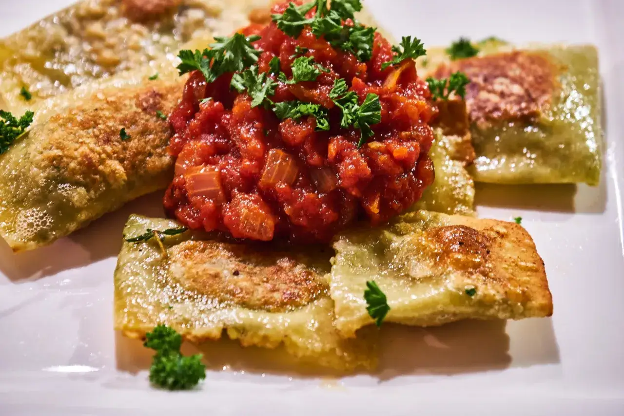 Goldbraun gebratene Ravioli mit frischer Tomatensauce und Petersilie – ein Genuss, der Lust auf die besten Ravioli Rezepte macht.