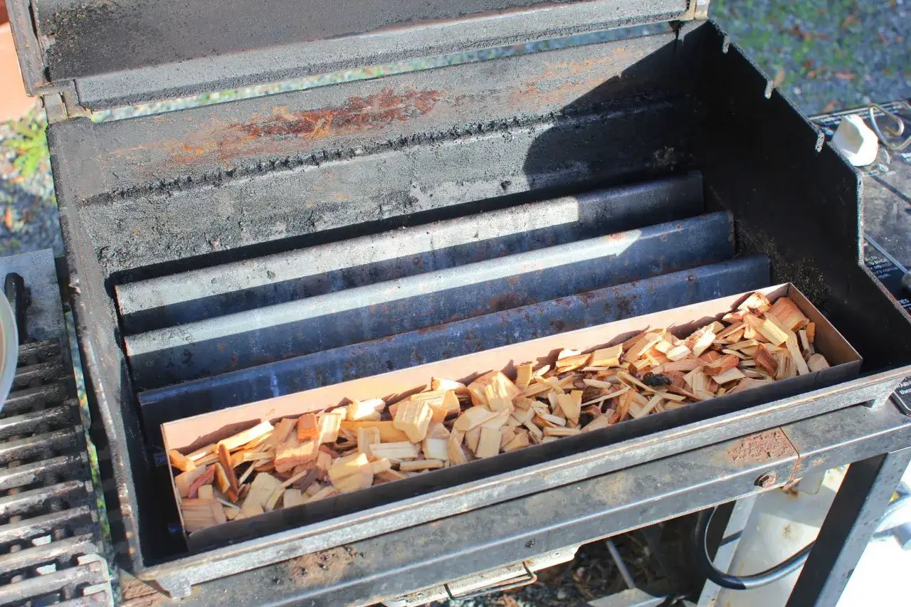 Bo&icirc;te remplie de copeaux de bois dans un barbecue, pr&ecirc;t &agrave; fabriquer un fumoir.