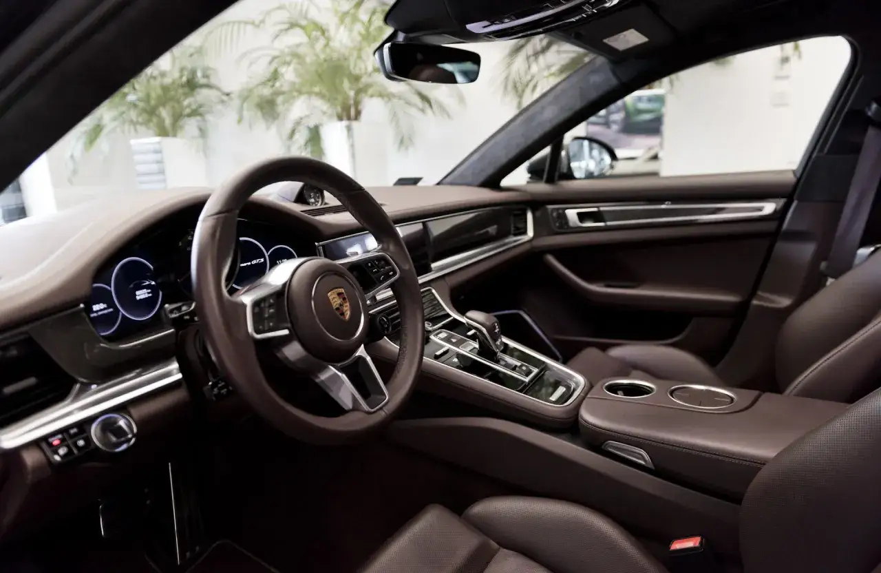 Wnętrze Porsche Panamera GTS z brązową skórzaną tapicerką, kierownicą i nowoczesnym panelem.