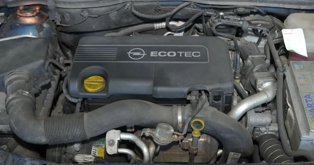 Silnik Ecotec z Opla Astry G CC. Widoczny jest czarny plastikowy kolektor z logo Opla i napisem Ecotec, żółty korek oleju oraz elementy układu dolotowego.