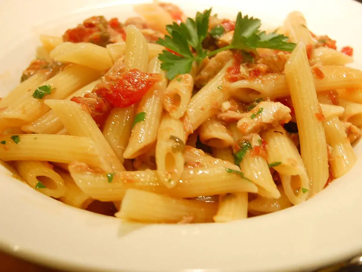 Penne-Nudeln mit einer herzhaften Tomatensauce und Thunfisch, garniert mit Petersilie. Ein k&ouml;stliches Gericht, das Lust auf mehr macht.