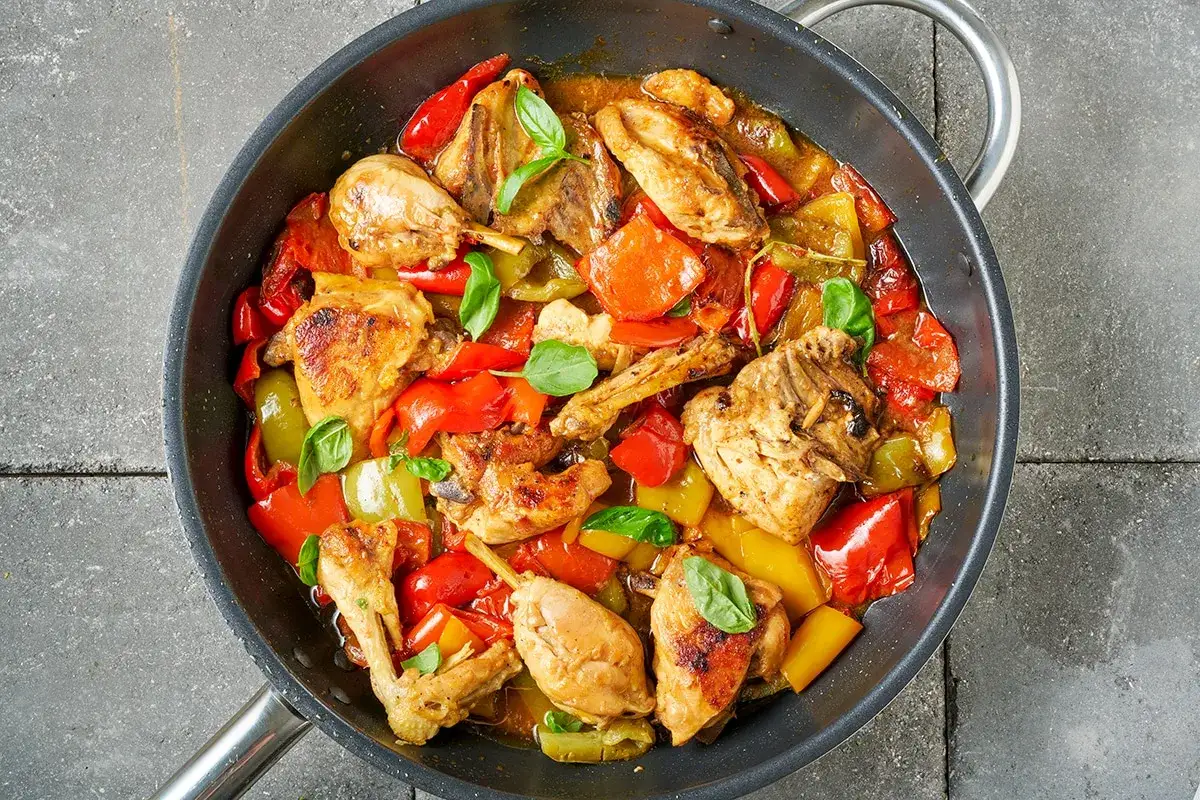 Un saporito pollo con peperoni rossi e gialli, cotto in padella con erbe aromatiche fresche.