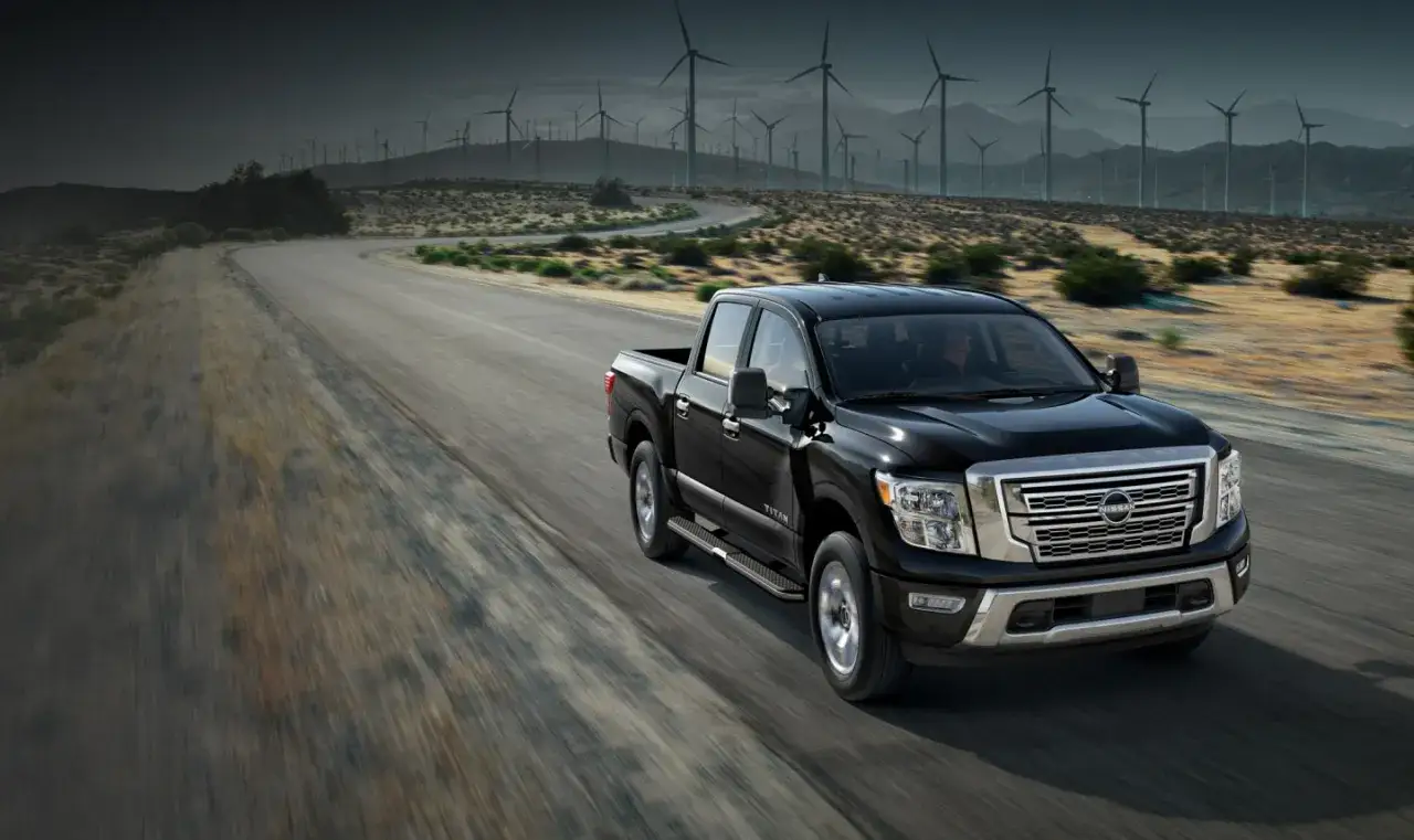 Czarny Nissan Titan jedzie po pustynnej drodze, w tle widać farmę wiatrową.